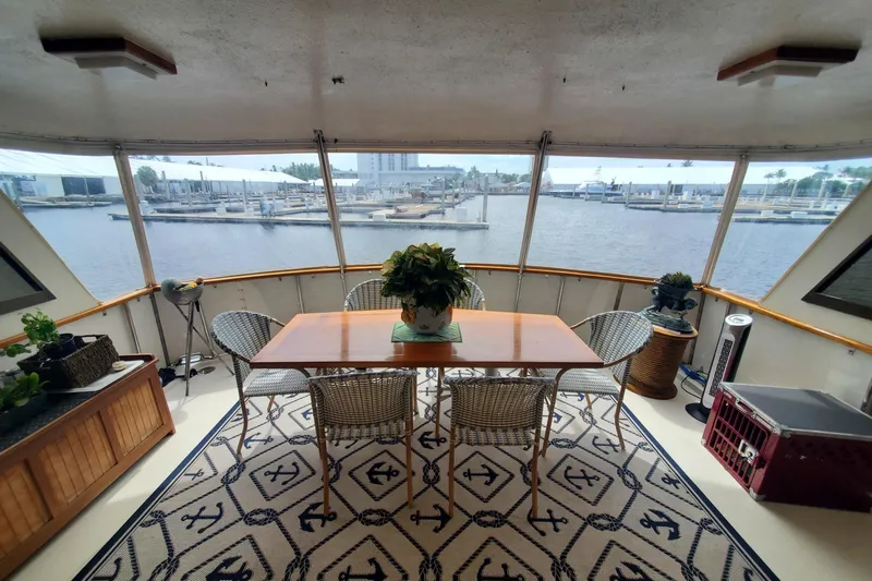 Ruby Yacht Photos Pics 1981 Hatteras 56 Motor Yacht interior with dining area, wicker chairs, and marina view.