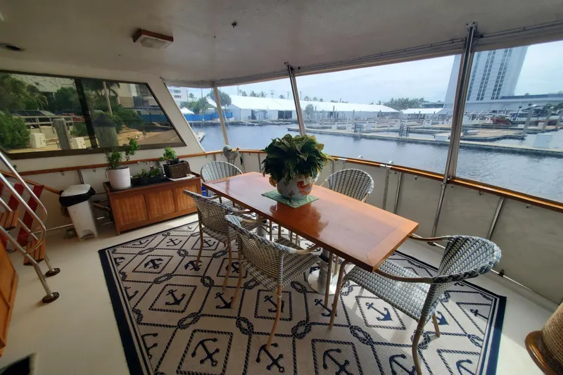 Ruby Yacht Photos Pics 1981 Hatteras 56 Motor Yacht interior with dining area, wicker chairs, and nautical-themed rug.