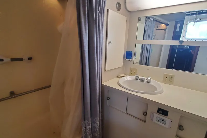 Ruby Yacht Photos Pics Bathroom interior of 1981 Hatteras 56 Motor Yacht with sink, mirror, and shower curtain.