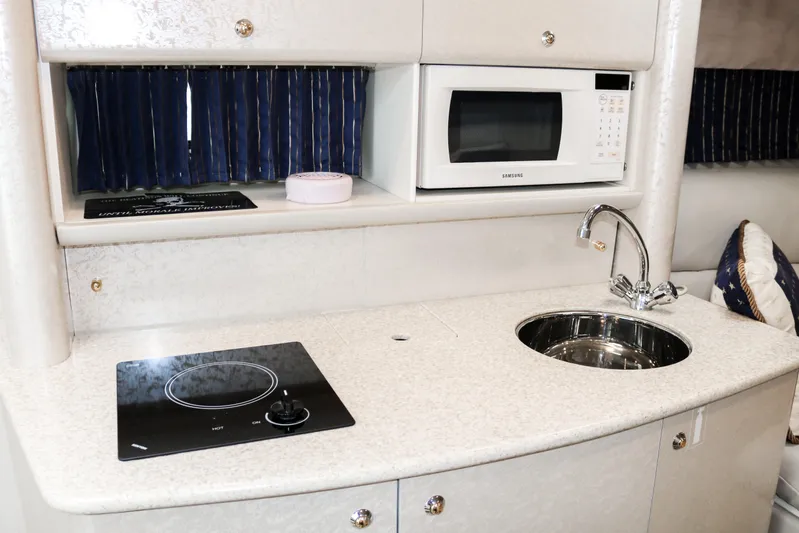  Yacht Photos Pics Compact kitchen area in a 2003 Formula 370 Super Sport boat with microwave, sink, and stovetop.