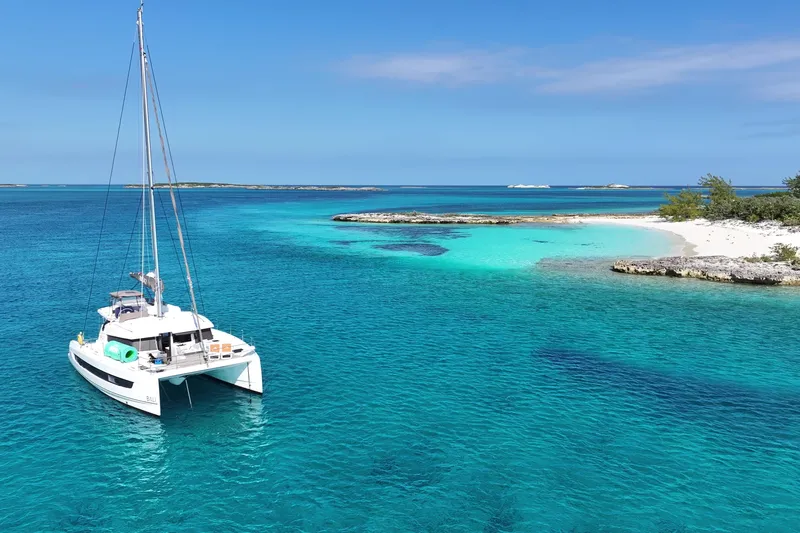 Cielo Yacht Photos Pics Sailing catamaran Bali 4.2, 2023 model, anchored in turquoise tropical waters near a sandy beach.