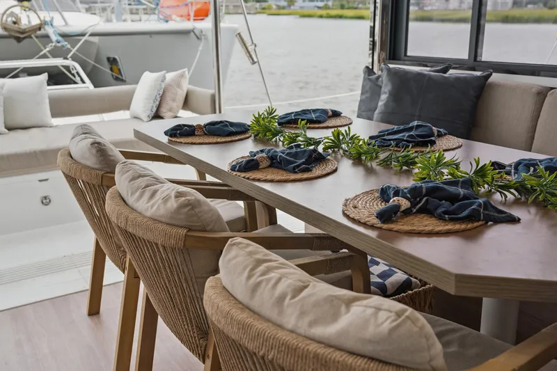 Cielo Yacht Photos Pics Elegant dining setup on a 2023 Bali 4.2 yacht, featuring woven chairs and nautical decor.