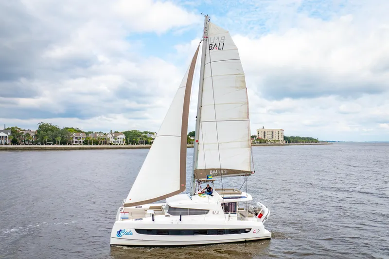 Cielo Yacht Photos Pics Sailing catamaran Bali 4.2, 2023 model, cruising on a calm river under cloudy skies.