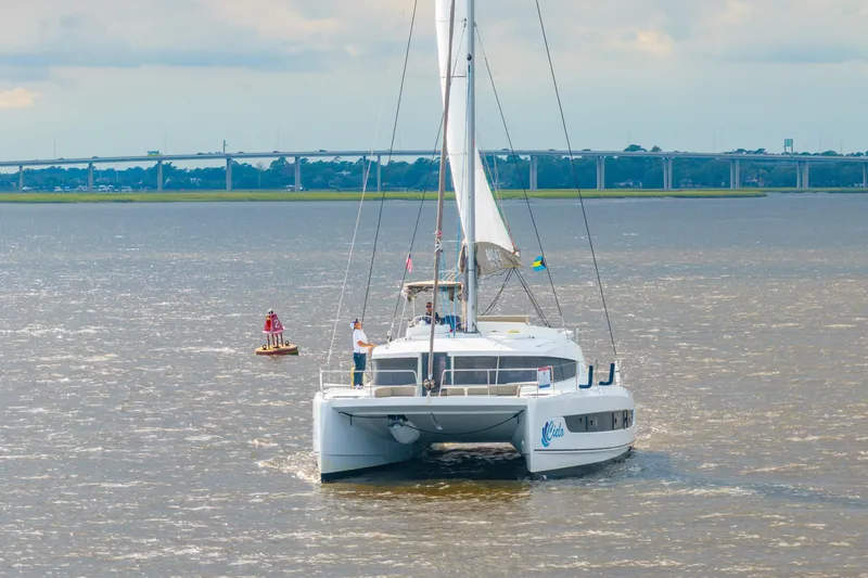 Cielo Yacht Photos Pics 2023 Bali 4.2 catamaran sailing on a river with a bridge in the background.
