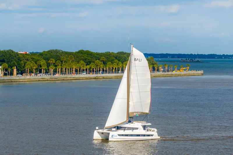 Cielo Yacht Photos Pics Sailing catamaran Bali 4.2, 2023 model, cruising near a scenic coastline with palm trees.