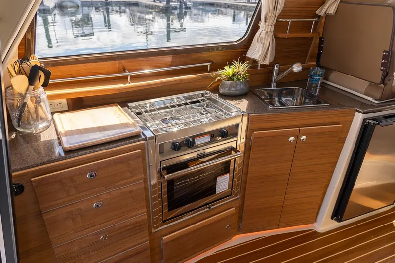  Yacht Photos Pics 2025 Ranger Tugs R-29 CB boat kitchen with stove, sink, and wooden cabinetry.