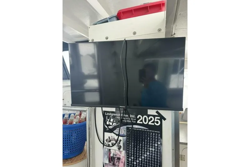 Annabel C Yacht Photos Pics Flat-screen TV mounted above a calendar, with a blue basket nearby.