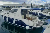 A 2015 Sas-Vektor 950 boat docked in a marina with a blue canopy.