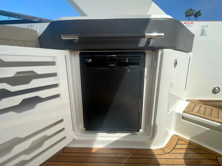 Honey Yacht Photos Pics 2019 Sea Ray SLX 310 boat interior with built-in mini fridge and wooden flooring.