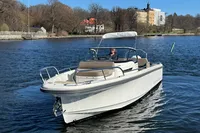 A 2020 Nimbus T8 boat cruising on a calm lake under a clear blue sky.