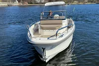 2020 Nimbus T8 boat cruising on a calm lake with a person at the helm.