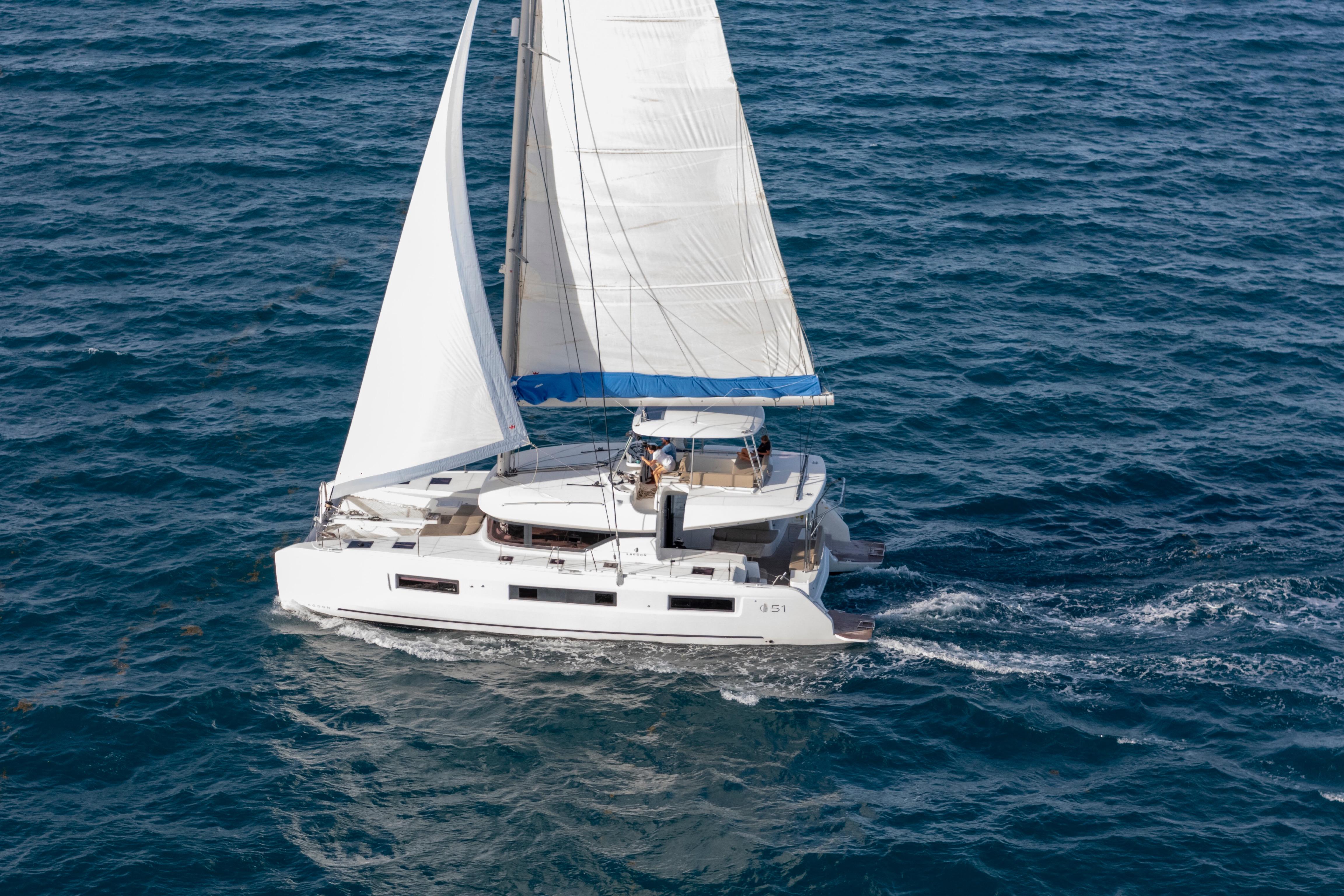 2024 Lagoon 51 sailing catamaran cruising on open sea with full sails.