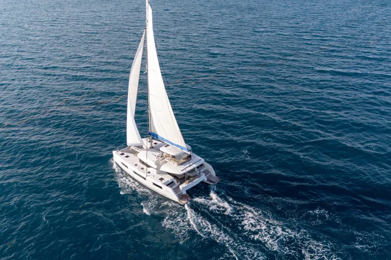 Bellissima Yacht Photos Pics 2024 Lagoon 51 catamaran sailing on open sea with white sails.