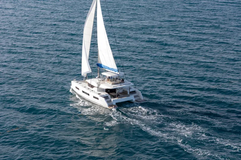 Bellissima Yacht Photos Pics 2024 Lagoon 51 catamaran sailing on open sea with white sails.