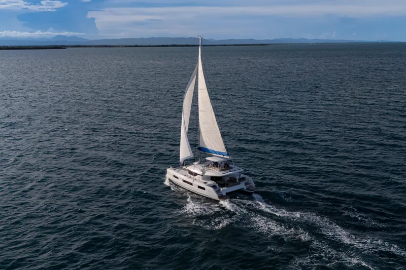 Bellissima Yacht Photos Pics 2024 Lagoon 51 catamaran sailing on open sea under clear skies.