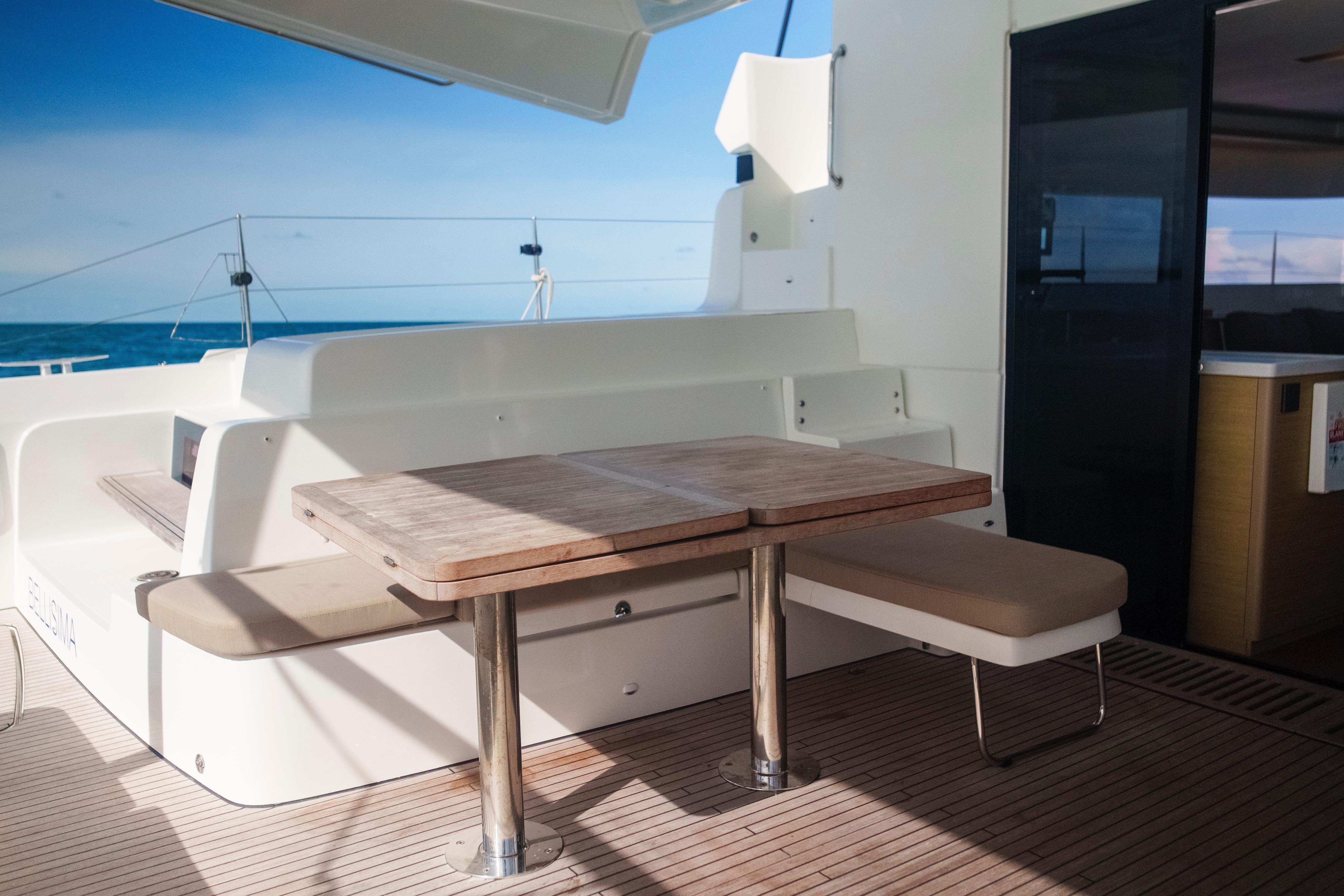 2024 Lagoon 51 yacht deck with wooden table and ocean view.