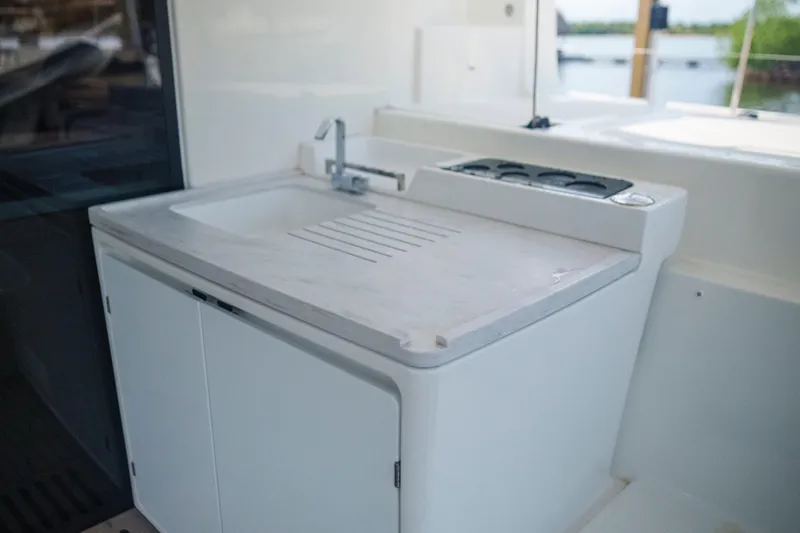 Bellissima Yacht Photos Pics 2024 Lagoon 51 yacht kitchenette with sink and stove, featuring sleek white cabinetry.