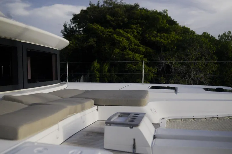 Bellissima Yacht Photos Pics Luxurious 2024 Lagoon 51 yacht deck with cushioned seating, surrounded by lush greenery.