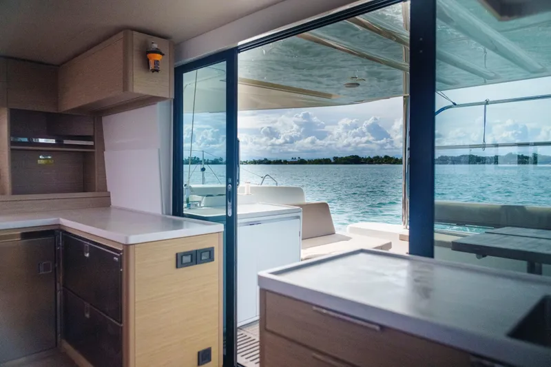 Bellissima Yacht Photos Pics Interior view of 2024 Lagoon 51 yacht with ocean backdrop through sliding doors.