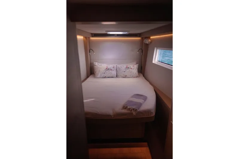 Bellissima Yacht Photos Pics Luxurious cabin interior of 2024 Lagoon 51 yacht with cozy bed and window view.