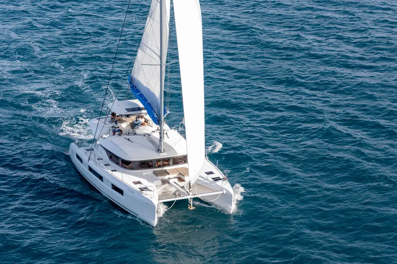 Bellissima Yacht Photos Pics 2024 Lagoon 51 catamaran sailing on open blue sea, aerial view.