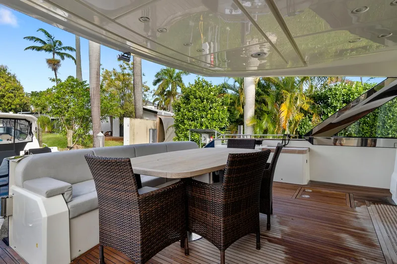 Knot @ Work Yacht Photos Pics Outdoor seating area on 2021 Monte Carlo Yachts MCY 76 Skylounge, featuring wicker chairs and table.