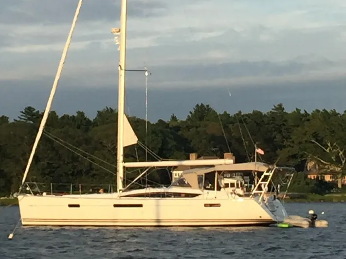 Spring Tide Yacht Photos Pics 2012 Jeanneau 53 sailboat anchored on a calm lake with a forested background.