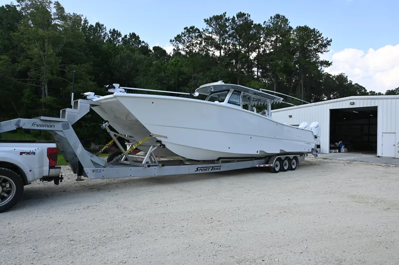  Yacht Photos Pics 2024 Freeman 43 boat on trailer near a white building, surrounded by trees.