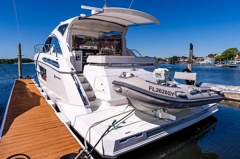 My Way Yacht Photos Pics 2019 Cruisers Yachts 54 Cantius docked with inflatable boat, sunny marina backdrop.