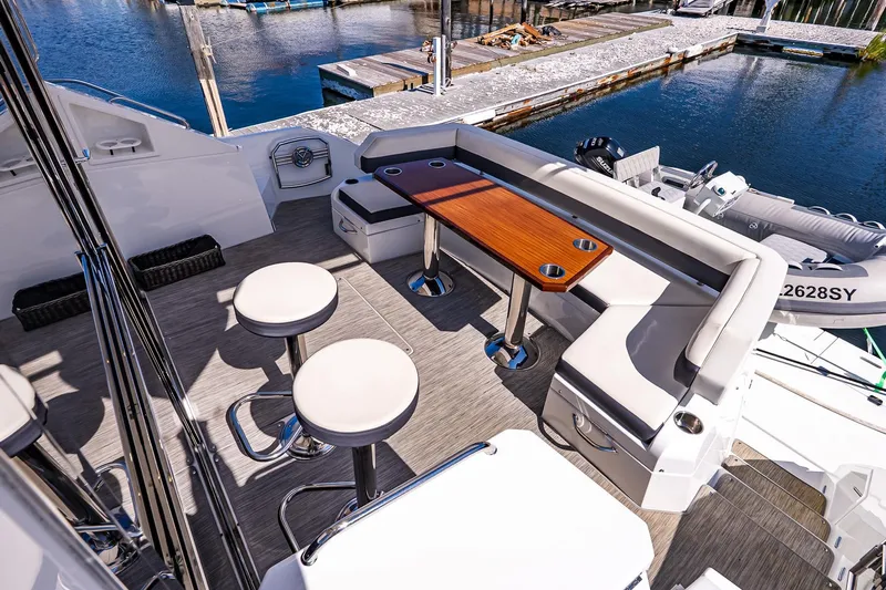 My Way Yacht Photos Pics Luxurious 2019 Cruisers Yachts 54 Cantius deck with seating and table, docked by the water.