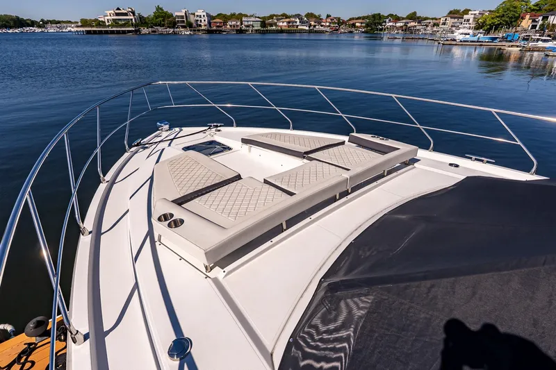 My Way Yacht Photos Pics 2019 Cruisers Yachts 54 Cantius bow with sun loungers on a serene waterfront.