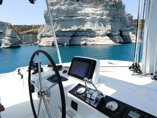  Yacht Photos Pics Lagoon 46 yacht cockpit with navigation equipment, steering wheel, and scenic rocky coastline view.