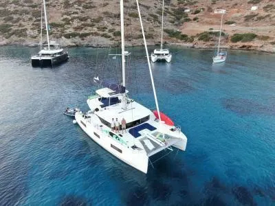  Yacht Photos Pics 2021 Lagoon 46 catamaran anchored in clear blue water, surrounded by scenic coastline.