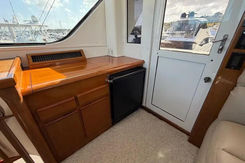 Maritere Yacht Photos Pics Interior of 1999 Viking 58 Convertible yacht with wooden cabinetry and small refrigerator.