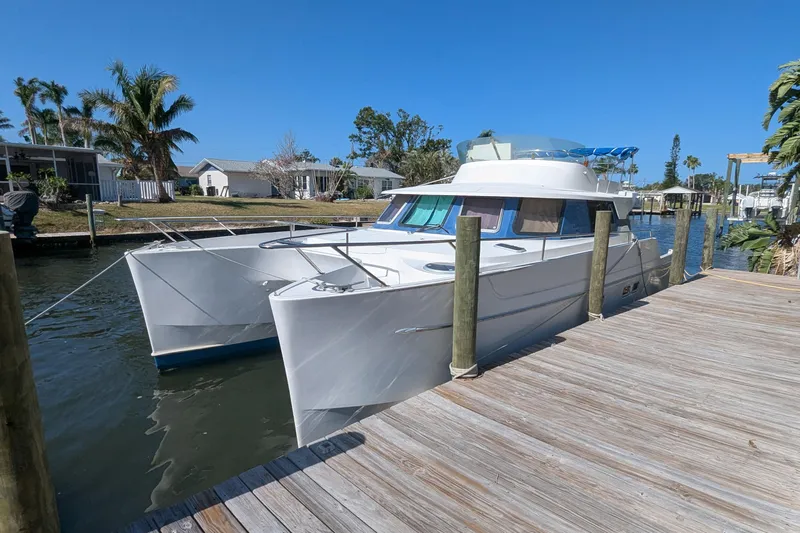 Sometimes Nancy Yacht Photos Pics 2003 Fountaine Pajot Maryland 37 catamaran docked by a wooden pier, under clear blue skies.