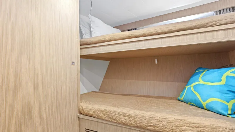 Chitochi Yacht Photos Pics Bunk beds in a 2016 Custom Line Ferretti Group yacht cabin, featuring wood paneling and colorful pillows.