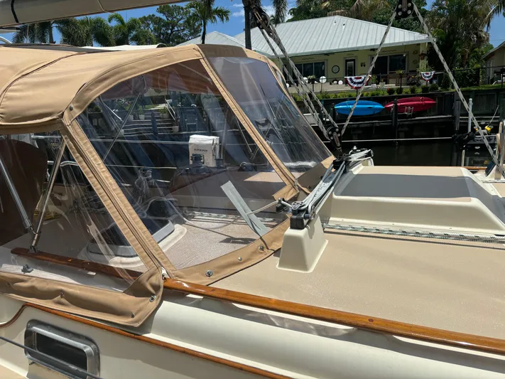 Island Girl Yacht Photos Pics 1990 Island Packet 38 sailboat with tan canvas cover and clear windows, docked near waterfront homes.