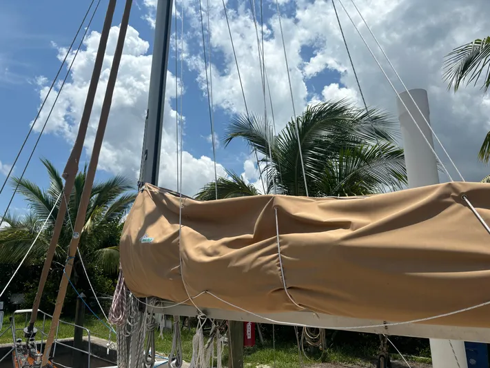 Island Girl Yacht Photos Pics Sailboat mast and boom of 1990 Island Packet 38 under a cloudy sky with palm trees.