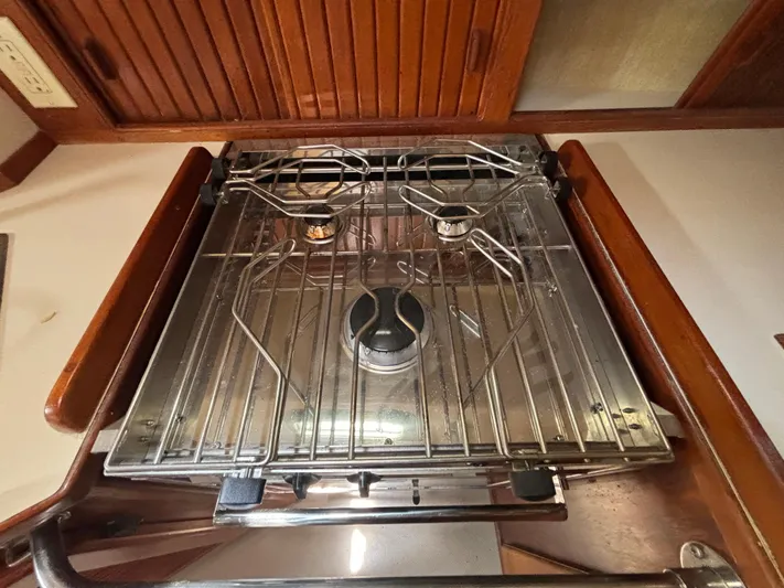 Island Girl Yacht Photos Pics Stove in 1990 Island Packet 38 sailboat galley, featuring two burners and wooden cabinetry.