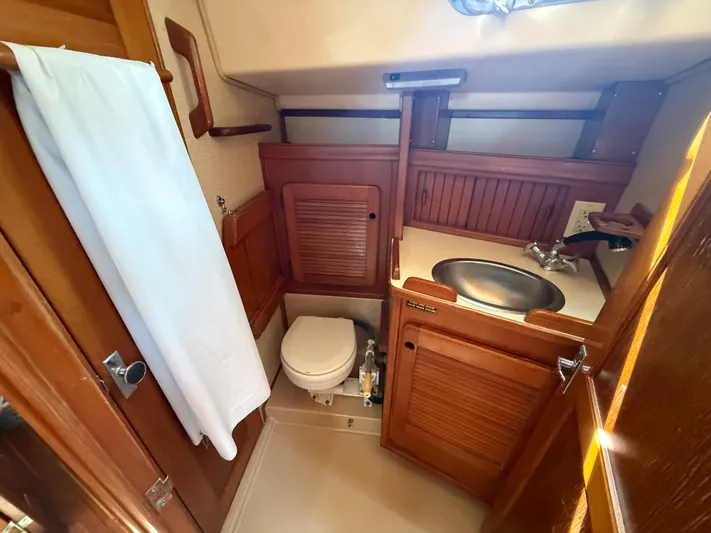 Island Girl Yacht Photos Pics 1990 Island Packet 38 sailboat bathroom with wooden cabinetry and compact design.