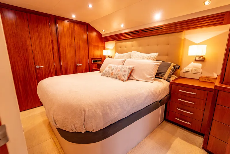 Baja Vida Yacht Photos Pics Luxurious bedroom interior of 2010 Hatteras 60 Convertible yacht with wood accents and cozy lighting.