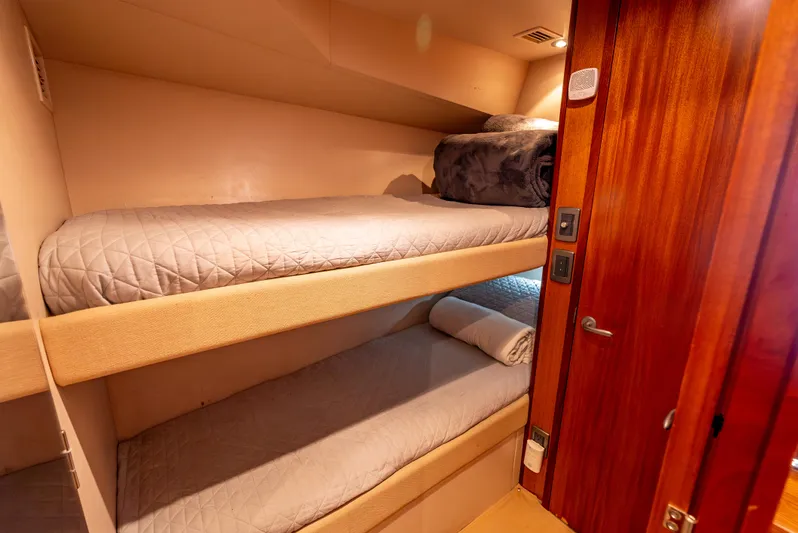 Baja Vida Yacht Photos Pics Bunk beds in 2010 Hatteras 60 Convertible yacht cabin with wooden door and cozy bedding.