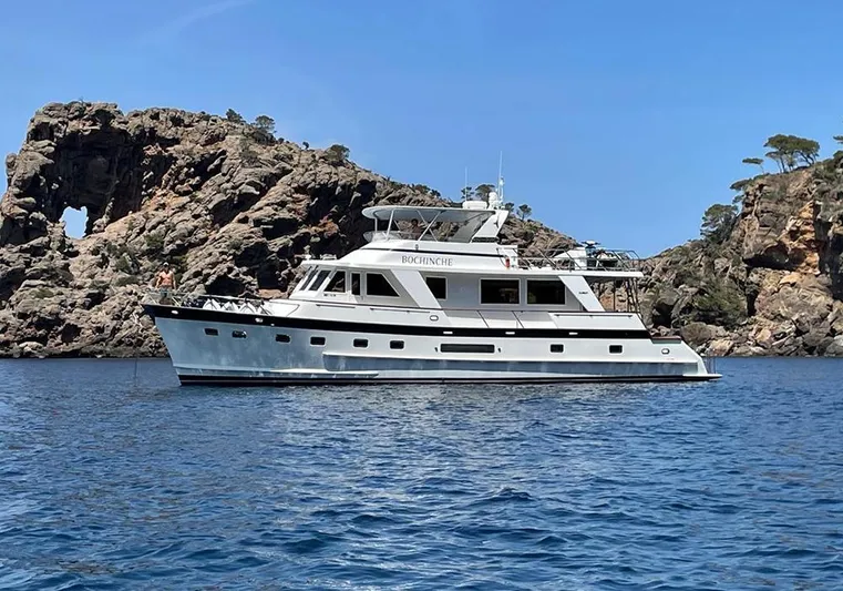 Bochinche Yacht Photos Pics 2006 Grand Alaskan 65 Flush Deck yacht on blue water near rocky cliffs.