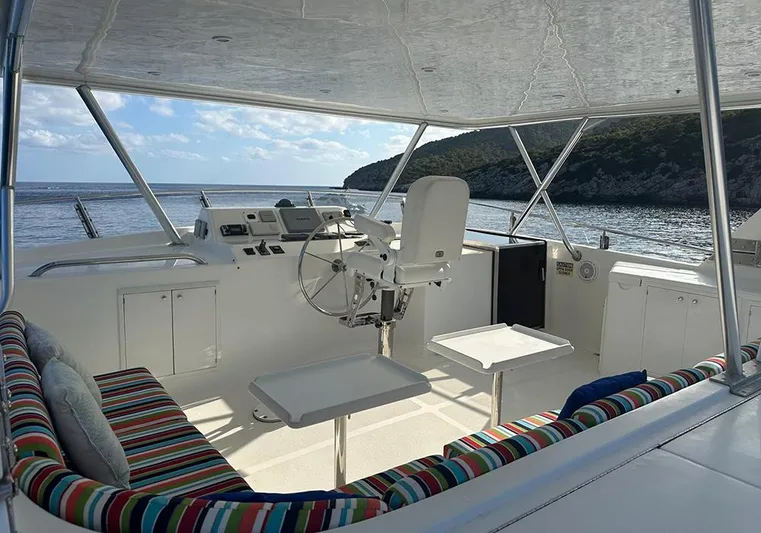 Bochinche Yacht Photos Pics 2006 Grand Alaskan 65 Flush Deck yacht interior with colorful seating, steering wheel, and ocean view.