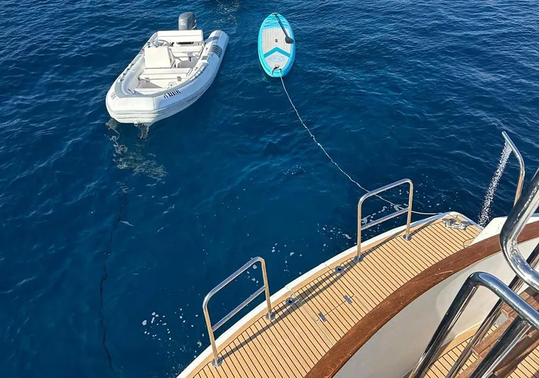 Bochinche Yacht Photos Pics Grand Alaskan 65 Flush Deck yacht with dinghy and paddleboard, 2006 model, on clear blue water.