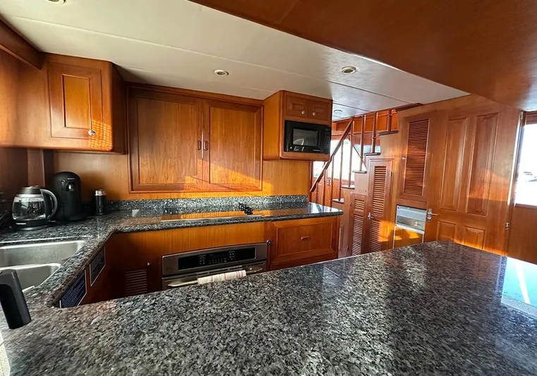 Bochinche Yacht Photos Pics Luxurious kitchen interior of 2006 Grand Alaskan 65 Flush Deck yacht with wooden cabinetry.