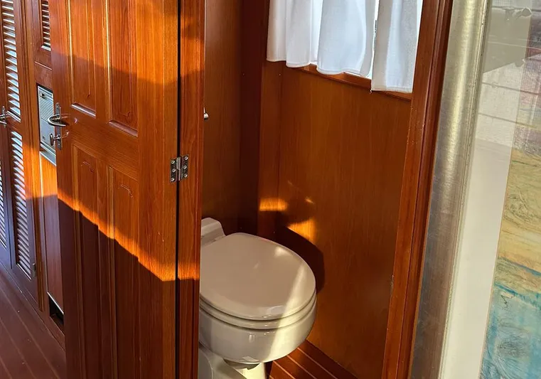 Bochinche Yacht Photos Pics Wood-paneled bathroom on 2006 Grand Alaskan 65 Flush Deck yacht with toilet and sunlight.