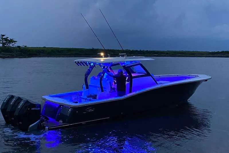  Yacht Photos Pics 2020 Scout 355 LXF boat illuminated with blue lights on water at dusk.