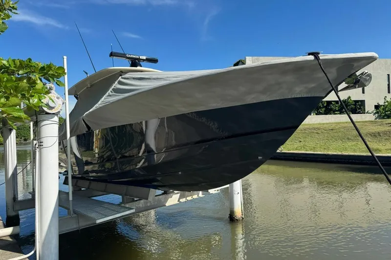  Yacht Photos Pics 2020 Scout 355 LXF boat on lift, covered, near water and greenery.