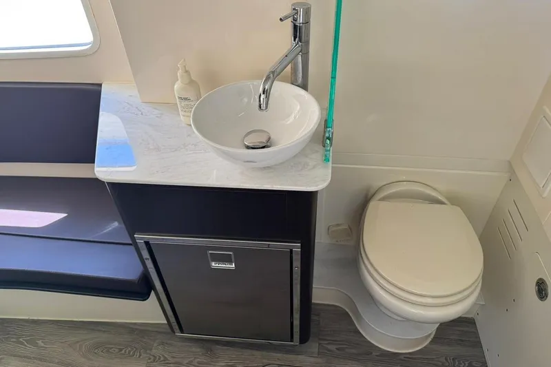  Yacht Photos Pics 2020 Scout 355 LXF boat bathroom with sink, toilet, and storage cabinet.